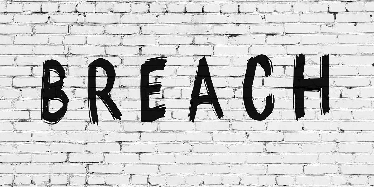 Inscription breach written with black paint on white brick wall.