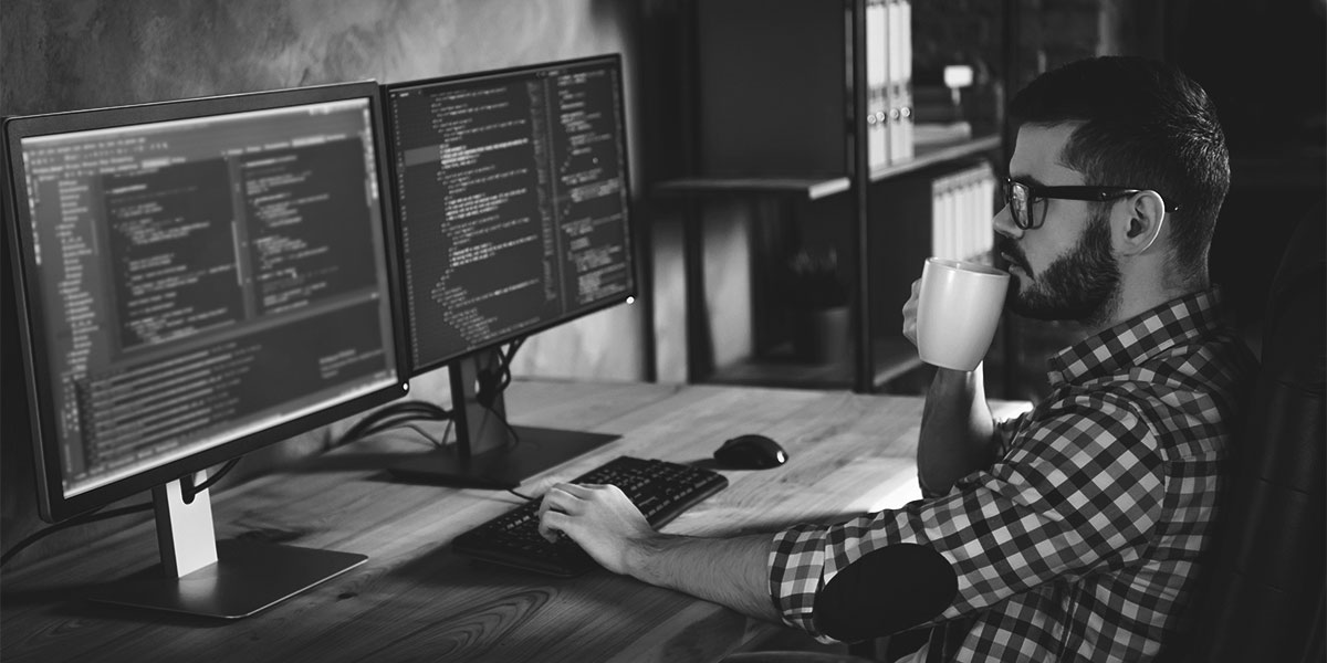 IT Administrator looking at code on their multi-screen work desk.