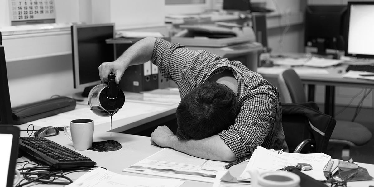 Überforderter Administrator schüttet versehentlich Kaffee neben seine Tasse.