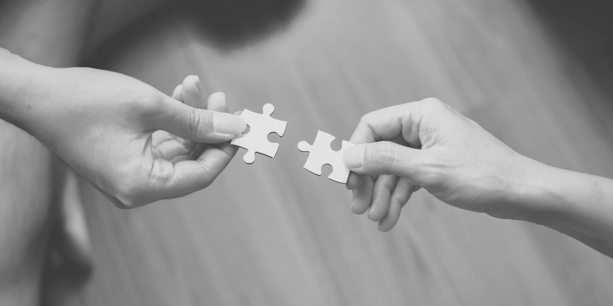 zwei Hände die ein Puzzle verbinden